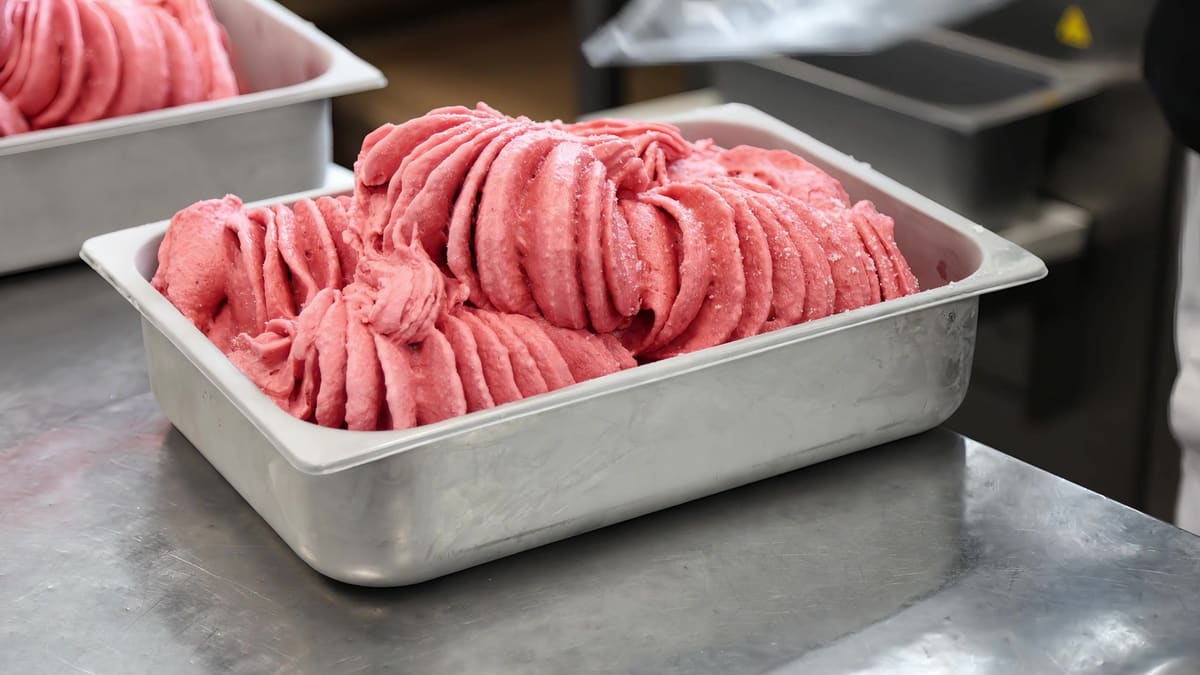 Różowe lody w stalowych kuwetach na blacie produkcji
