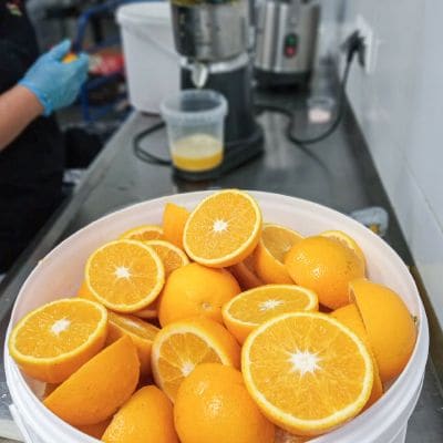 Połówki pomarańczy w misie przy wyciskarce do soków